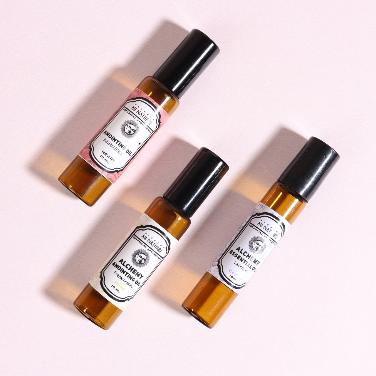 three bottles of essential oils on a pink background